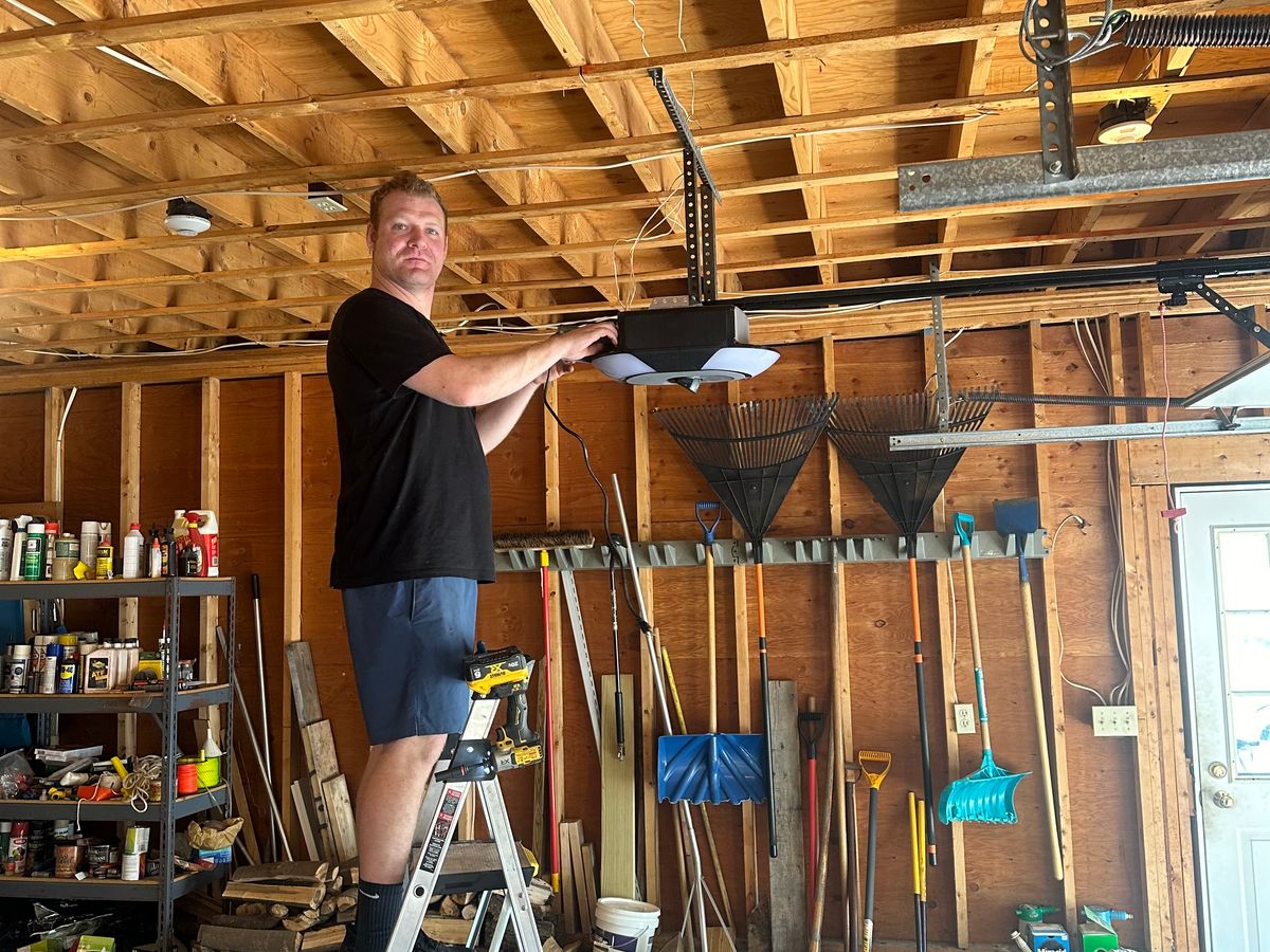 Murray technician working on torsion spring installation from ladder in residential garage